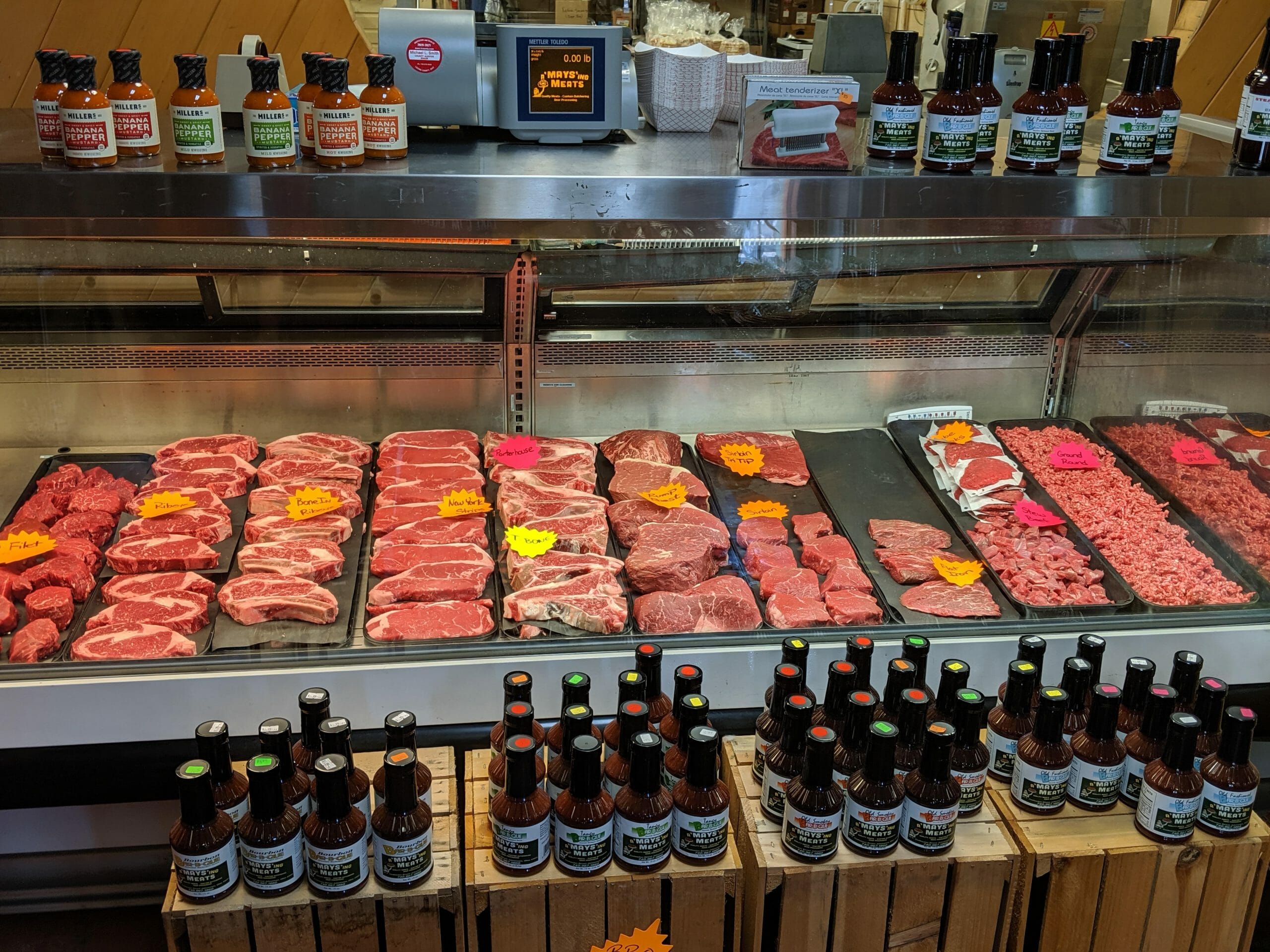 Butcher shop meat display case with fresh beef and bottled sauce